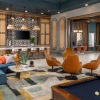 Mid century style community lounge area with seating and neon sign at The Weldon by Broadstone apartments in McDonough, GA